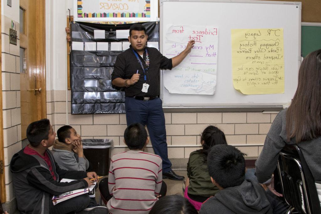 小学老师哈泽尔·罗曼·拉古纳斯站在教室前面，学生们坐在他前面的地板上.