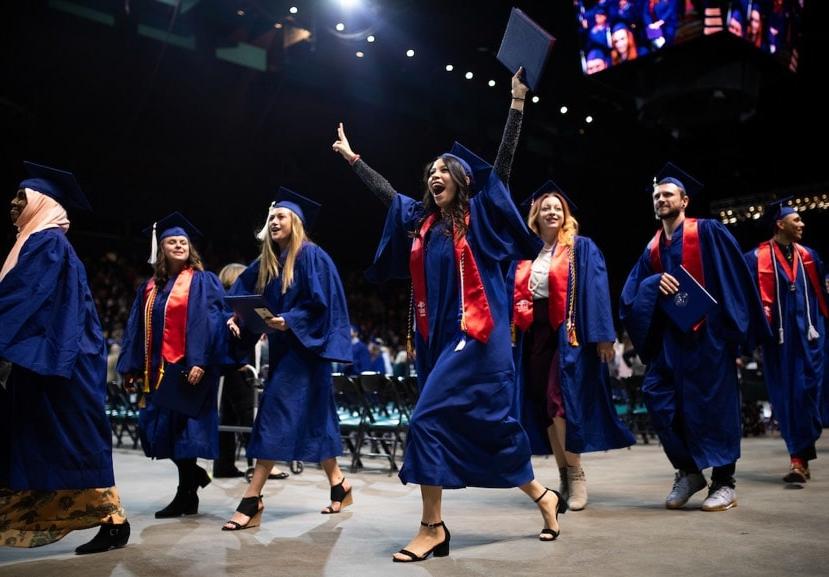 MSU Denver graduates walk off the Commencement stage with their diplomas.
