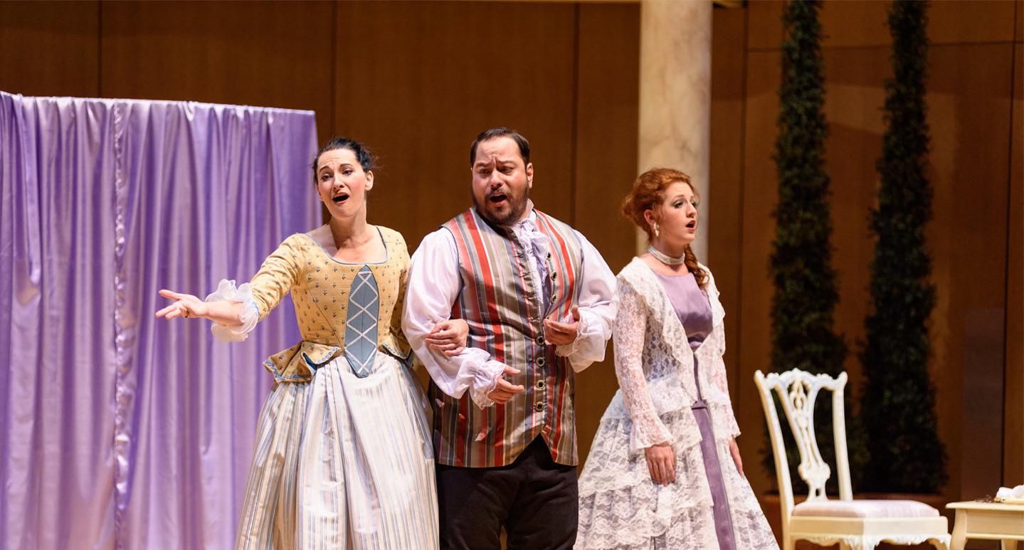 三位歌剧演员在舞台上穿着时代服装表演费加罗