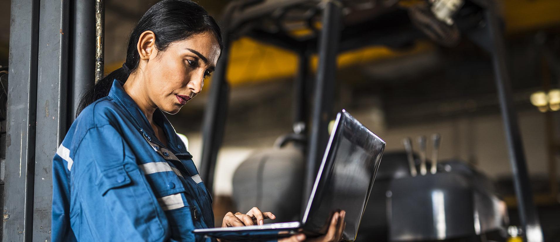 印度女钢铁厂工人在叉车前使用笔记本电脑
