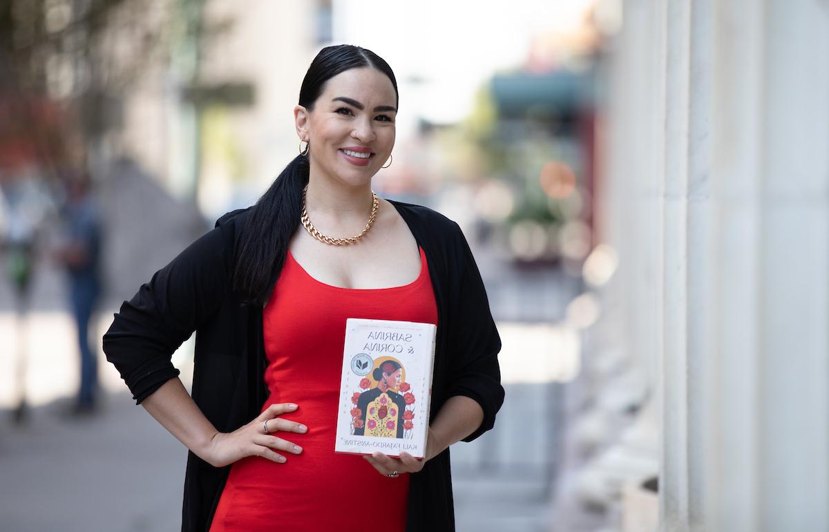 作家Kali Farjardo-Anstine拿着她的书《塞布丽娜》 & 科瑞娜